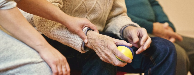 Eldre kvinne holdes på håndleddet av yngre kvinner
