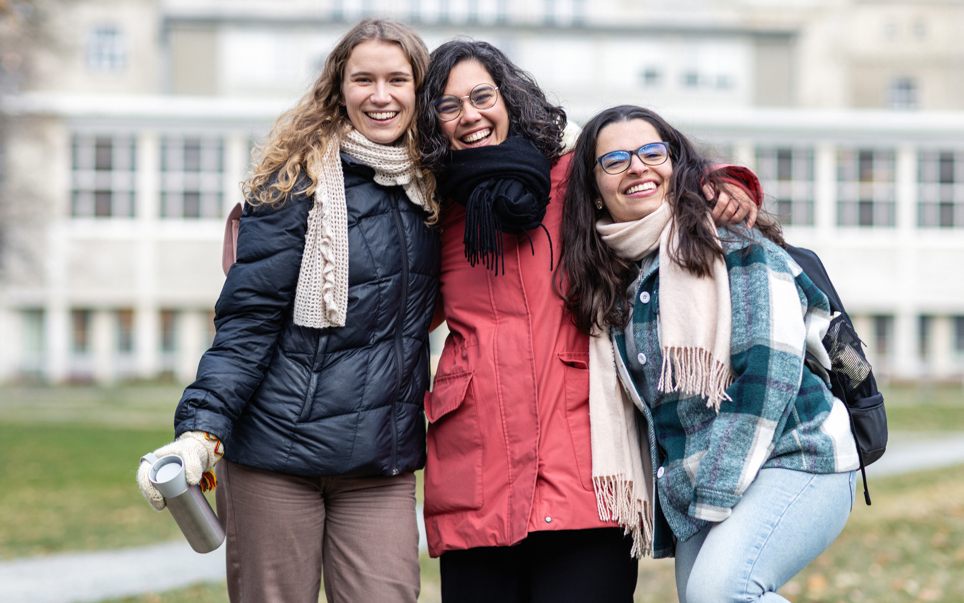 Tre smilende studenter, på campus. Foto