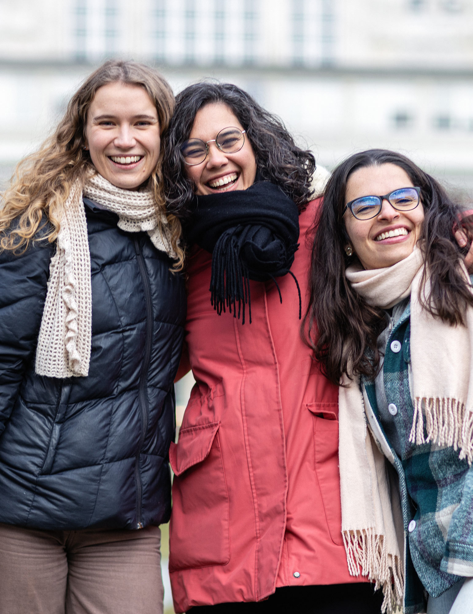 Tre smilende studenter, på campus. Foto