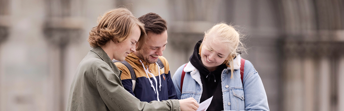 Tre studenter som leser i ei bok. Foto