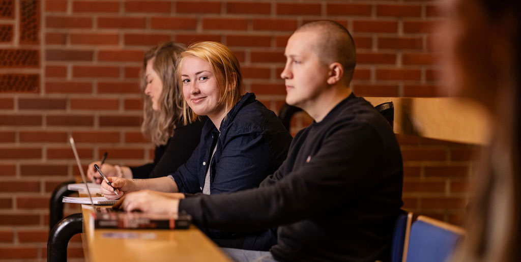 Tre studenter i forelesningssal. Foto