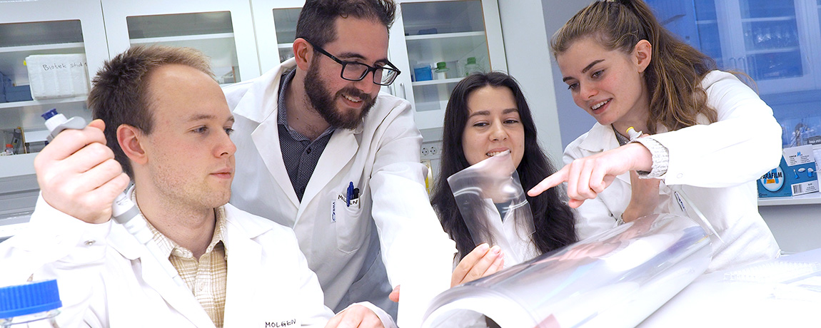 Tre studenter med veileder i et laboratorium. Foto