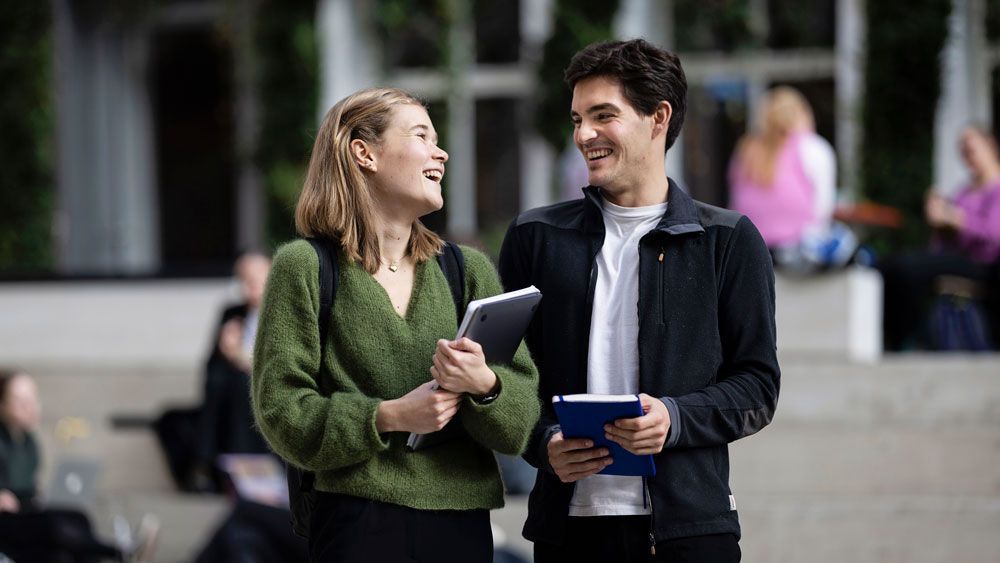 To studenter som står sammen og ler 