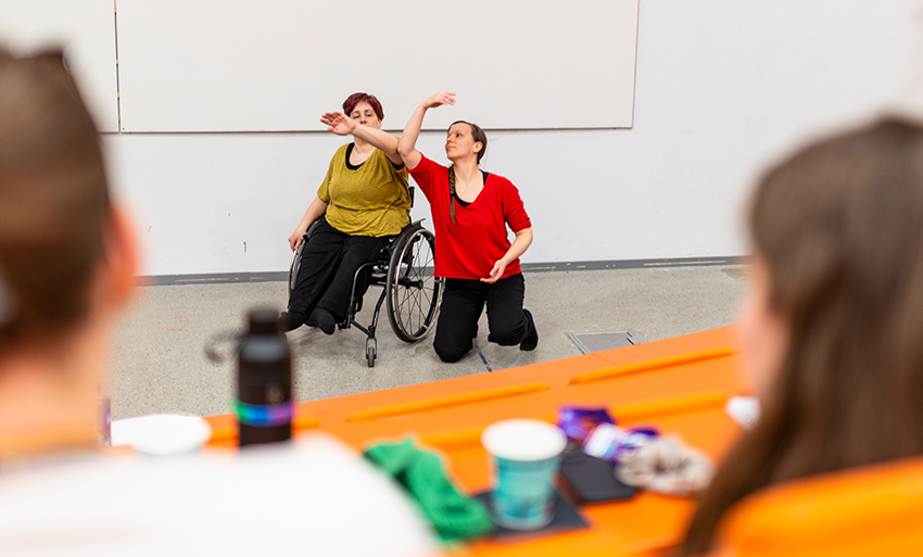 A person in a wheelchair, a person sitting on the floor. Photo