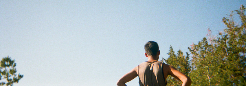 Is seen from behind, with a young boy/man. Blue sky. 