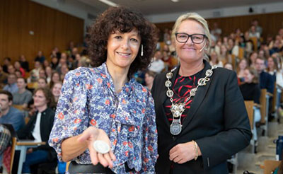 Foto av Charpentier og prorektor Hernes. Charpentier holder frem medaljen hun har fått tildelt.