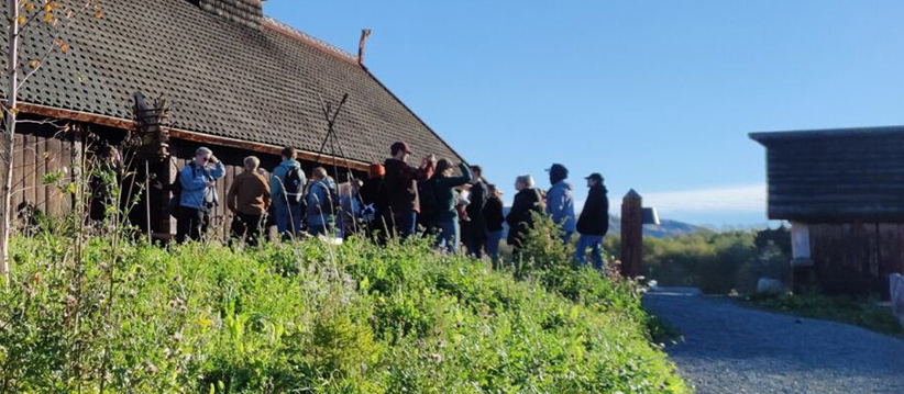 Studenter står ved et langhus. Foto