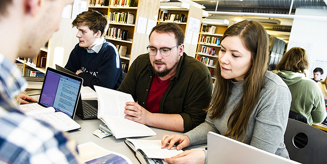 Studenter sitter og jobber med pc-er og notater. Foto