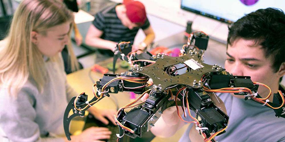 En kvinnelig og mannlig student jobber jobber med en drone i laboratoriet. Foto: Børge Sandnes/NTNU.