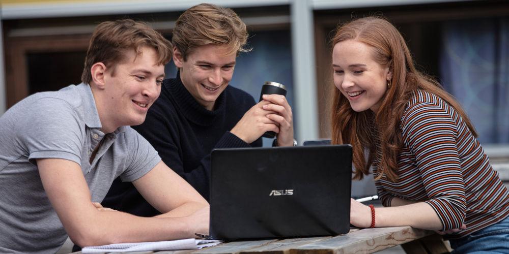 Tre studenter på marin teknikk sitter ute og samarbeider. Foto: Geir Mogen/NTNU.