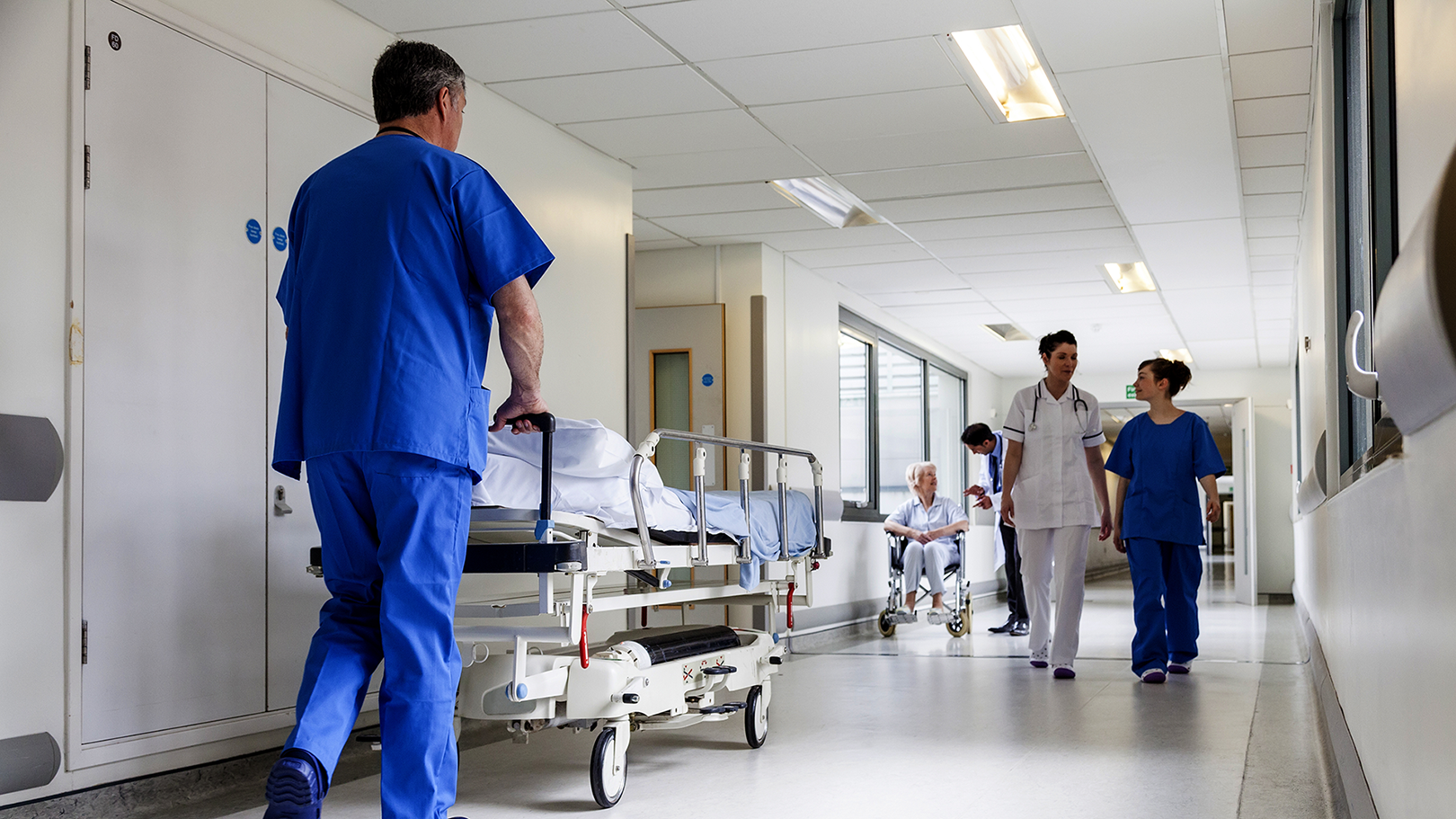 Gang på et sykehus med ansatt som triller sykeseng. Foto: shutterstock