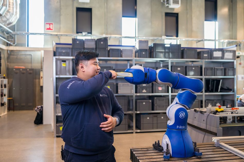 Student tar en "fist bump" med en maskinrobot i S-laboratoriet